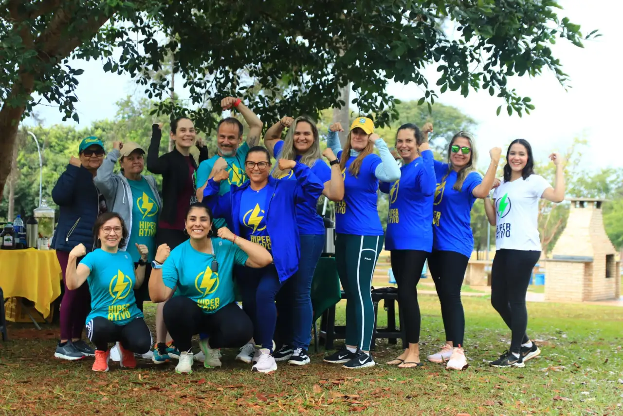 Grupo Hiperativo reunido sob as árvores, com participantes sorrindo e usando camisetas do grupo.