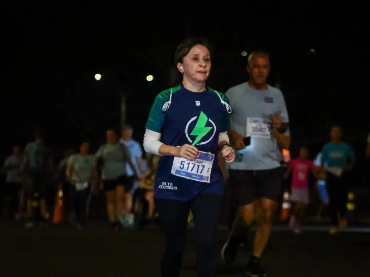 Cristianne, de camiseta azul do Hiperativo, participando de uma corrida à noite.